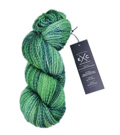 a skein of green and blue yarn on a white background with a black tag