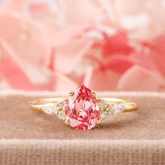 a pink and white diamond ring sitting on top of a table next to some flowers