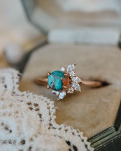 A close up image showing the "Aurae" engagement ring from Staghead Designs. This 14K rose gold ring features asymmetrical floral diamond accents made up of marquise and round diamonds around a round cabochon cut spiny oyster turquoise. Spiny oyster turquoise is a composite stone made up of turquoise, pyrite, and orange spiny oyster shell. Rings Engagement Western, Diamond And Turquoise Engagement Ring, Western Rings Engagement, Engagement Ring With Turquoise, Turquoise And Diamond Ring, Western Wedding Rings, Turquoise Engagement Ring, Turquoise Ring Engagement, Vintage Turquoise Ring