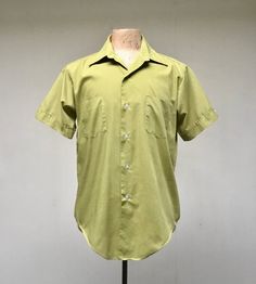 * Men's casual shirt c 1970s* Green polyester-cotton blend fabric * Medium pointed collar* Double chest patch pockets * Short, set-in sleeves with sewn down notched cuff with button detail* Action pleats below back yoke* 6 button front closure* Long tailsLabel: Master Built - Permanent Press - 15 1/2Excellent conditionChest: 44Shoulder: 18Sleeve: 9Length: 31 (center back)Garments are flat-measured. Please compare these measurements to another flat-measured garment that fits you correctly for siz Fitted Cotton Camp Shirt With Spread Collar, Retro Shirt With Johnny Collar And Relaxed Fit, Vintage Cotton Short Sleeve Shirt With Camp Collar, Retro Cotton Collared Camp Shirt, Vintage Cotton Shirt With Johnny Collar, Retro Collared Short Sleeve Shirt Relaxed Fit, Retro Cotton Short Sleeve Shirt, Vintage Short Sleeve Collared Shirt With Pockets, Retro Short Sleeve Collared Shirt With Pockets