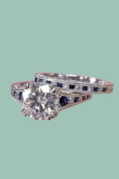 This classic, hand-crafted large center diamond solitaire engagement ring from Kirk Kara is stunning and elegant. Its 0.08-carats total weight side diamonds and 0.25-carats side blue sapphires are channel-set on a band with hand-engraved milgrain and filigree details. Sparkling peek-a-boo diamonds and additional side engraved details enhance the breathtaking design of the Kirk Kara Stella. Kirk Kara Engagement Rings, Channel Set Diamond Engagement Ring, Engagement Rings Channel Set, Blue Sapphire Diamond, Diamond Engagement Ring Set, Antique Inspiration, Diamond Solitaire Engagement Ring, Channel Set, Engagement Ring Wedding Band