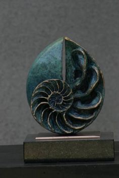 a bronze sculpture with a nautish shell on it's base, sitting on a black stand