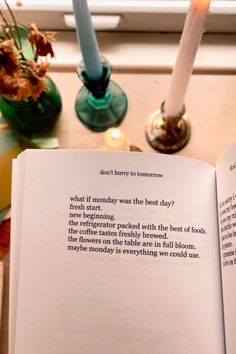 an open book sitting on top of a table next to two candles and some flowers