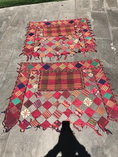 two rugs are laying on the ground next to each other, with one being held up by someone's hand