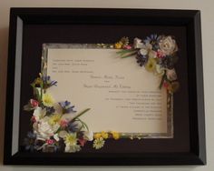 a black frame with flowers on it and a white sheet of paper in the middle