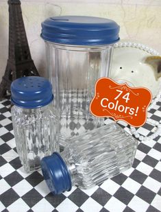 two clear and blue plastic cups sitting on top of a checkered tablecloth next to the eiffel tower