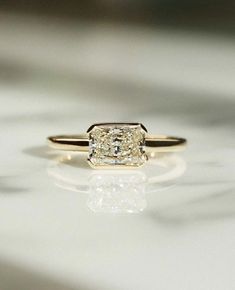 a diamond ring sitting on top of a white surface with the reflection of it's face