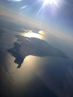 the sun shines brightly over water from an airplane window as it flies through the sky