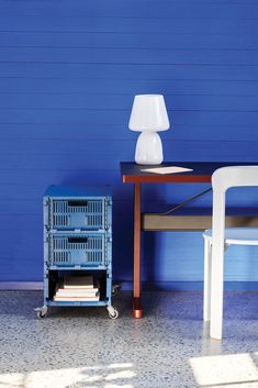 a table with a lamp next to a blue wall