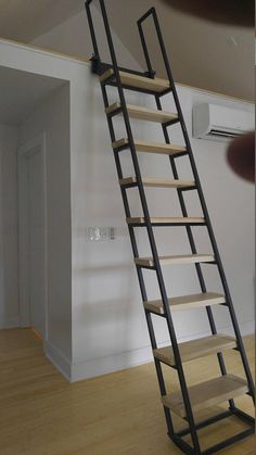 a ladder that is sitting in the middle of a room with wood flooring and white walls