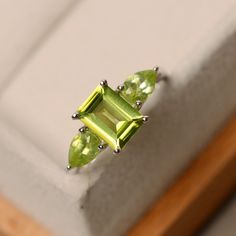 This ring features a 6*8mm emerald cut peridot and sterling silver finished with rhodium. Customization is available. It is made by hand, and it will take about 7 days to finish the ring after your payment is completed. Main stone: Peridot Main stone weight: Approx 1.70 ct Metal type: sterling silver finished with rhodium Accent stone: peridot Customization is available, I also can make it with 14k solid gold (white or yellow or rose), just feel free to contact me. Any question, just let me know Multi Stone Engagement Ring, Fantasy Jewellery, Green Stone Jewelry, Mom Things, Mothers Ring, White Smile, Mother Rings, August Birthstone, Stone Engagement Ring