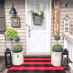 two planters with flowers are sitting on the front porch next to a welcome sign