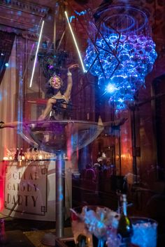 a woman standing on top of a table in front of a chandelier