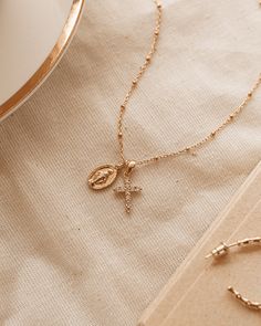 The Protégée Necklace means protected in French. This delicate charm necklace with Madonna and her cross are both iconic and beautiful, reminding you that you are protected. The Madonna pendent is gold plated silver 8x13.5mm and 2mm thick. Petite rhinestone cross features Cubic Zirconia on gold plated silver 10.5x15.5x2mm. Gold Filled chain 18 inches. Madonna Jewelry, Parisian Wedding, Cross Necklace Women, Cross Jewelry Necklace, The Madonna, Christian Necklace, Catholic Jewelry, Rhinestone Cross, Gold Cross Necklace