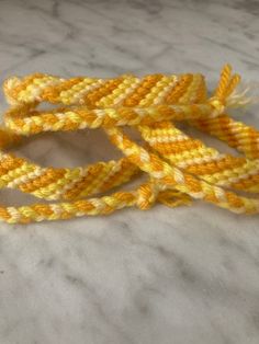 This bracelet is made of acrylic yarn in three different colors: saffron, bright yellow, and lemon. The bracelet has knot closures, which are adjustable. It can easily slide on over your hand, and then be adjusted for a tighter fit. Cheap Handmade Yellow Friendship Bracelets, Cheap Yellow Everyday Friendship Bracelets, Yellow Items, Yellow Friendship Bracelets For Beach, Yellow Adjustable Friendship Bracelets As Gift, Casual Yellow Friendship Bracelets With Sliding Knot, Yellow Braided Friendship Bracelets, Yellow Friendship Bracelets With Adjustable Cord As Gift, Adjustable Yellow Bracelets For Friendship