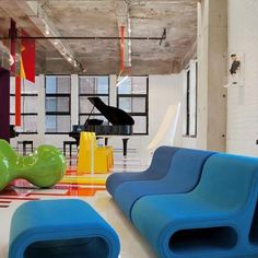 an office with colorful chairs and piano in the back drop off area, while another chair sits on the floor next to it