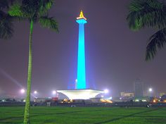 there is a tall blue tower in the middle of a field at night time with palm trees around it