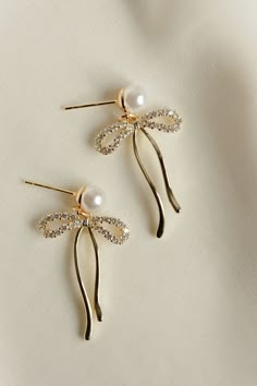 Rumor has is that 2024 is the year of BOWS! These super cute, dangly bow pearl stud earrings will be the HIT of any party. Includes two gold or silver-plated CZ sparkly dangly bow charms 6mm 14k gold-filled or sterling silver, hypoallergenic pearl studs Gold Earrings Fancy, Trendy Gold Pearl Earrings For Party, Gold Glamorous Jewelry With Bow, Glamorous Gold Jewelry With Bow, Gold Dainty Pearl Earrings For Party, Dainty Gold Pearl Earrings For Party, Gold Pearl Earrings With Bow For Gift, Gold Pearl Earrings With Bow As Gift, Sparkling Pearl Drop Earrings Gift