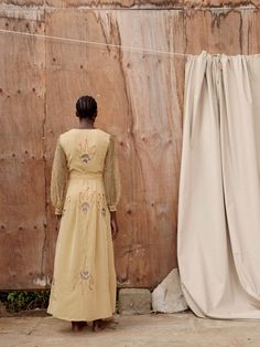 Beautiful and timeless, Hamaji’s signature flame yellow maxi dress takes inspiration from Kenya’s rich and diverse flora. Large embroidered botanical designs decorate the body of the dress, whilst the sleeves feature a more intricate pattern. Pair with burnt orange shoes to accentuate the tassels and stitch detail. Fit:This silk crepe dress has a loose silhouette with a tie-fastening at the waist and structured bell sleeves, is fully lined and features pockets. Silk Maxi Dress With Floral Embroidery, Silk Floral Embroidered Floor-length Maxi Dress, Festive Maxi-length Embroidered Dress, Festive Maxi Embroidered Dress With Embroidered Sleeves, Festive Maxi Dress With Embroidered Sleeves, Festive Silk Maxi Dress With Floral Embroidery, Fitted Silk Dresses With Embroidered Sleeves, Fitted Maxi Dress With Embroidered Sleeves, Silk Dress With Embroidered Long Sleeves