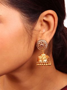 This timeless and classic traditional Kamalika Jhumka exemplifies intricate craftsmanship and detailed design. Its stud section displays a round flower design, embellished with the graceful beauty of white zircon stones, and at the center of the motif, vibrant red and green semi-precious stones. Crafted from 925 sterling silver and polished to a lustrous gold finish. Available in two different colors:  Red and white stones, Green and white stones. Please refer to the pictures of the jewelry worn Temple Jewelry Earrings With American Diamond, Bollywood Style Intricate Design Jhumkas, Fusion Style Intricate Chandbalis For Reception, Festival Jhumkas, Traditional Round Cubic Zirconia Bridal Earrings, Reception Chandbalis With Tilla Detail, 22k Gold Chandbalis For Wedding, 22k Gold Round Chandbalis For Wedding, Elegant Heavy Yellow Gold Jhumkas