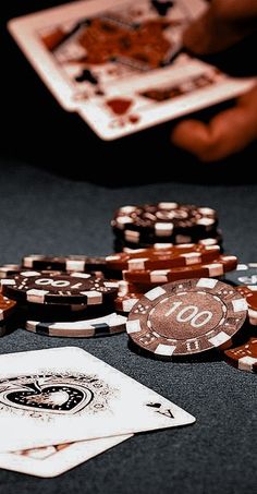 poker chips and playing cards on a table with two hands reaching for the winning chip