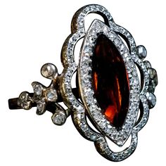 a ring with an orange stone surrounded by white and clear stones on it's sides