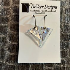 a pair of silver earrings sitting on top of a card