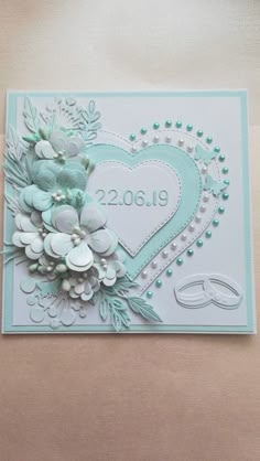 a wedding card with flowers and pearls in the shape of a heart on a table