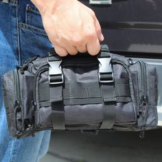 a man is holding a black bag in his hand while standing next to a truck