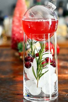 a glass filled with liquid and ice on top of a wooden table next to christmas decorations