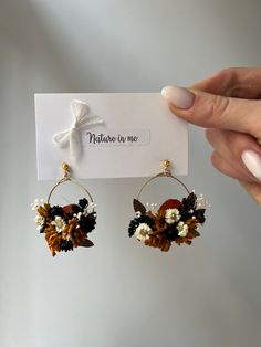 a pair of earrings with flowers on them and a white ribbon tied to the ear