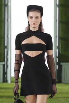 a model walks down the runway in a black dress with sheer sleeves and cutouts