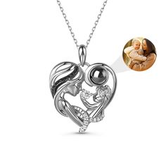 This is a mysterious necklace, personalized for the moment you love most on a projection necklace! Crafted in sterling silver, this endearing necklace representing a mother holding her child features a heart-shaped frame with a dangling projection stone and smaller stones embellishing the mother’s curvy hair. The baby is naughtily playing and the mother looks at her child patiently with love. The beautiful lines embody the gentle, graceful mother’s love. She always protects her naughty and innoc Elegant Silver Birthstone Necklace As Gift For Mom, Elegant Silver Birthstone Necklace For Mom, Personalized White Gold Necklace For Mother's Day, Silver Necklaces For Mother's Day, Mother's Day White Gold Birthstone Necklace Gift, Silver Necklace For Mother's Day, White Gold Necklaces For Mother's Day Personalized Gift, Black Necklaces For Anniversary And Mother's Day, Sterling Silver Necklaces For Mother's Day