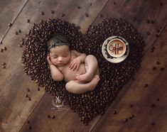 a baby sleeps in a heart - shaped basket with coffee beans and a cappuccino