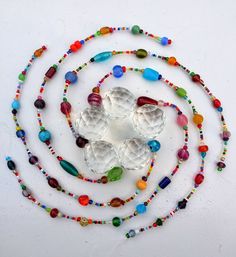 a beaded necklace with several beads and white shells on the end, surrounded by multicolored glass beads