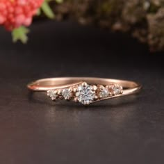 a diamond ring sitting on top of a table next to a pink flower bouquet and branch