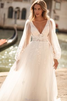 a woman in a white wedding dress standing next to a gondola and water