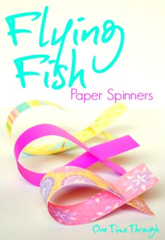 paper spinners with the words flying fish on it and one pink ribbon attached to them