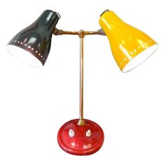 two desk lamps sitting on top of a red base with white and yellow lights in the middle