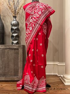 Elevate your ethnic elegance with our exquisite Red Kantha Stitch Saree crafted from luxurious Bangalore Silk, Silk Mark Certified. This saree is adorned with delicate white floral motifs, adding a touch of timeless charm to your wardrobe. Embrace the allure of tradition and sophistication as you drape yourself in this resplendent ensemble. Make a statement on any occasion with this beautifully handcrafted piece that captures the essence of grace and style. Occasion: Party, Festival, Wedding Fabric: Tassar Silk Certification: Silk Mark Work: Woven, Kantha Stitch, Hand-painted Fall / Pico:  Included Blouse Piece: Has matching blouse piece Shipping: Ships from the USA Made in India Please note that the actual color of the apparel in photos may vary slightly due to lighting and screen setting Red Tussar Silk Pre-draped Saree With Motifs, Festive Silk Pre-draped Saree With Motifs, Red Embroidered Pre-draped Saree For Eid, Embroidered Red Pre-draped Saree For Eid, Red Tussar Silk Sets With Cutdana Detail, Red Dola Silk Sets With Motifs, Dola Silk Salwar Kameez With Motifs, Red Raw Silk Pre-draped Saree For Traditional Ceremonies, Red Pre-draped Saree With Resham Embroidery For Traditional Ceremonies