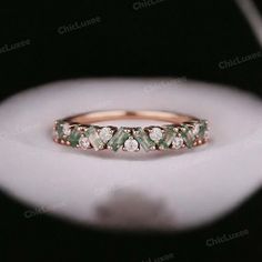 a close up view of a wedding ring with green and white stones