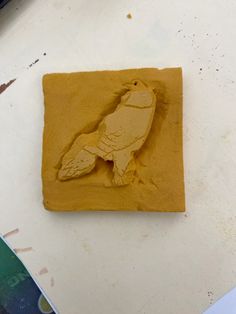 a clay carving of a bird sitting on top of a table