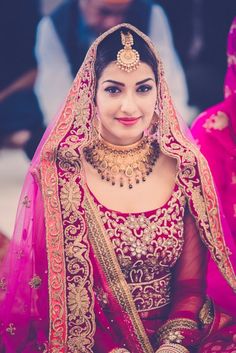 a woman wearing a red and gold bridal outfit