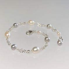 Premium-quality white and gray freshwater pearl bracelet, wire-wrapped in sterling silver This elegant and classic bracelet is designed with genuine gray and creamy-white freshwater pearls. The pearls are alternated and wire-wrapped to short segments of double strand sterling silver chain. This bracelet is completed with a sterling silver lobster claw clasp.  It is enlarged to show details.  Pearls are one of June's birthstones. Details: *  length: please choose at check-out gray semi-round f/w pearls:  3.5-4 mm  creamy white oval f/w pearls: 4x5 mm sterling silver chain and other components *  Choosing your length at checkout:  I recommend 1/2 inch larger than your actual wrist/ankle size. Bracelet/anklet is measured from end-to-end including clasp. Thanks for visiting ! Back to my shop f Affordable White Beaded Bracelets With Pearl Chain, Cheap Pearl White Bracelets For Gifts, Cheap Silver Jewelry With Pearl Charm, Luxury White Pearl Drop Beaded Bracelets, Luxury White Pearl Bracelet In Sterling Silver, Cheap Adjustable Pearl Bracelet With Silver Beads, Luxury Pearl White Bracelet With Pearl Charm, Cheap White Pearl Chain Bracelet, Luxury White Bracelet With Pearl Charm