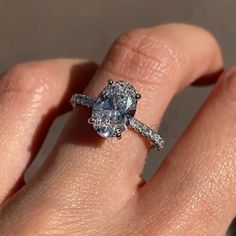 a woman's hand with a diamond ring on top of her finger and an engagement band