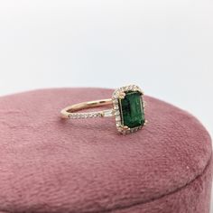 This ring features a beautiful emerald set in a halo ring setting with sparkling natural diamonds all set in 14k solid yellow gold. This design features two tapered baguette diamond accents in the shank. A gorgeous modern look that's perfectly balanced between minimalist and glamour. Green Diamond Ring With Halo Design, Emerald Cut Emerald Ring With Halo Design, Emerald Cut Halo Emerald Ring For May Birthstone, Green Emerald Diamond Ring With Halo Design, Formal Emerald Cut Emerald Ring With Halo, Green Diamond Cluster Ring With Halo Setting, Green Emerald Cut Ring With Halo Design, Emerald Rings With Halo Setting For Proposal, Emerald Diamond Ring With Halo Design For May Birthstone