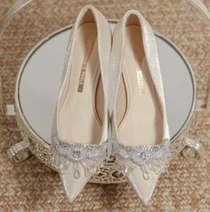 two pairs of wedding shoes sitting on top of a glass table in front of a mirror