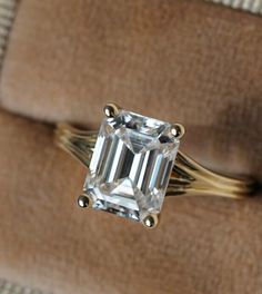 an engagement ring with a large emerald cut diamond on it's shanty band