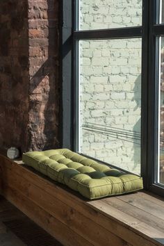 a green cushion sitting on top of a window sill next to a brick wall