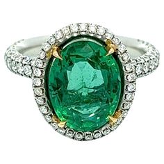 This exquisite ring boasts a 4.91-carat oval-shaped Colombian emerald, elegantly encircled by round diamonds that gradually taper down halfway on both sides. The emerald is set in platinum, ensuring maximum security and stability. You can rest assured of its top-notch quality and authenticity as it is GIA certified. This ring is bound to capture attention and make a bold fashion statement wherever you go. In Dept Description Emerald: 3.61CT Total Weight, Color Green, Oval Shape Diamonds: 1.36CT Luxury Oval Tsavorite Ring, Gia Certified Oval Green Diamond Ring, Oval Emerald Ring With Pave Setting In Platinum, Oval Emerald Ring With Pave Diamond Setting, Oval Emerald Ring With Diamond Pave Setting, Oval Emerald Rings With Pave Setting, Oval Emerald Ring In White Gold With Diamond, Oval Emerald Ring With Pave Setting For Anniversary, Gia Certified Oval Emerald And Diamond Ring